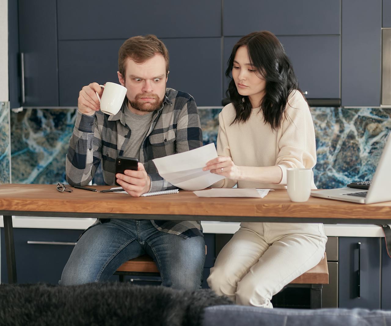 A couple looks concerned while reviewing financial documents together at home.